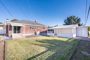 Back of house featuring a lawn and an outdoor structure