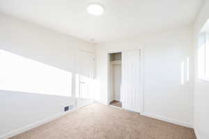 Unfurnished bedroom featuring light carpet and a closet