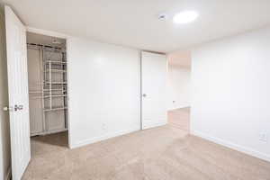 Unfurnished bedroom with light colored carpet, a closet, and a spacious closet