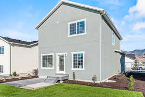 Rear view of house featuring a garage, a yard, and a mountain view