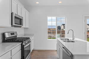 Kitchen with white cabinets, appliances with stainless steel finishes, sink, and a healthy amount of sunlight