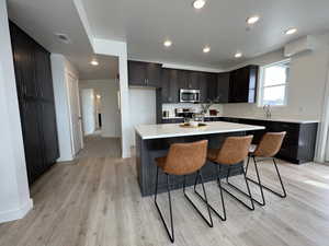 Kitchen with sink, a kitchen bar, stainless steel appliances, a center island, and light hardwood / wood-style floors