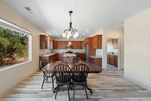 Dining area featuring light wood-type flooring, sink, a chandelier, and a wealth of natural light