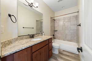 Full bathroom with hardwood / wood-style floors, vanity, toilet, and tiled shower / bath combo