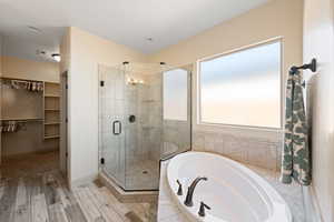 Bathroom with shower with separate bathtub and wood-type flooring