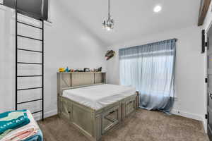 Bedroom featuring a notable chandelier, dark colored carpet, and lofted ceiling