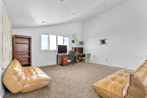 Home office featuring light colored carpet and lofted ceiling