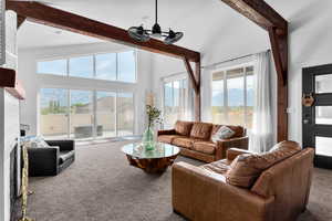 Living room with high vaulted ceiling, beamed ceiling, and a healthy amount of sunlight