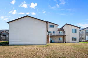 Back of house with a balcony and a yard