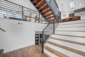 Stairway with a high ceiling, wood walls, a skylight, and hardwood / wood-style flooring