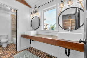 Full bathroom with vaulted ceiling, sink, bathtub / shower combination, and toilet