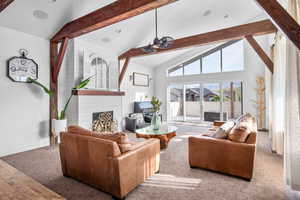 Living room featuring wood-type flooring, beam ceiling, high vaulted ceiling, and a large fireplace