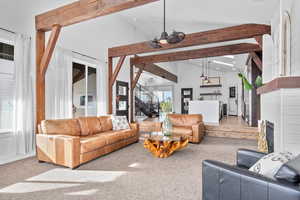 Carpeted living room featuring high vaulted ceiling and beamed ceiling