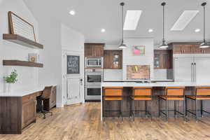 Kitchen featuring a kitchen breakfast bar, a skylight, hardwood / wood-style flooring, and tasteful backsplash