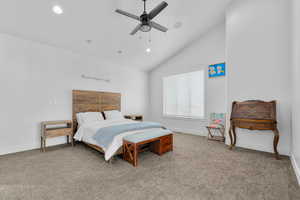 Carpeted bedroom featuring ceiling fan and high vaulted ceiling