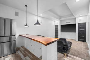 Kitchen with pendant lighting, stainless steel refrigerator, dark hardwood / wood-style flooring, and wooden counters