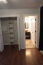 Unfurnished bedroom with ceiling fan, a closet, connected bathroom, and dark hardwood / wood-style flooring