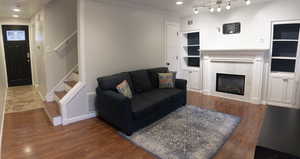 Living room featuring ornamental molding, a tiled fireplace, and dark hardwood / wood-style floors