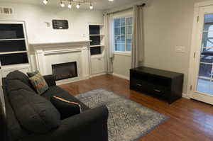 Living room featuring a tiled fireplace and dark wood-type flooring