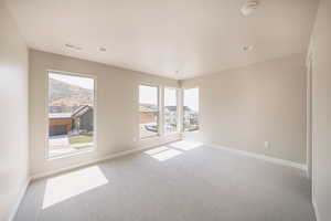 Unfurnished room featuring carpet flooring, a mountain view, and plenty of natural light