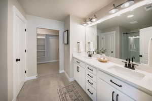 Bathroom with tile patterned flooring, vanity, and a shower with door