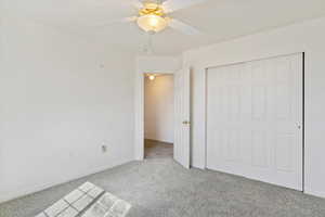 Unfurnished bedroom with ceiling fan, light colored carpet, and a closet