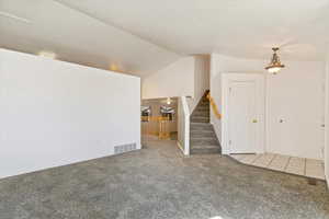 Unfurnished living room featuring vaulted ceiling and carpet flooring