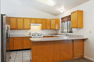 Kitchen featuring sink, stainless steel fridge, gas range gas stove, and kitchen peninsula