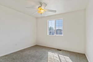 Carpeted spare room featuring ceiling fan