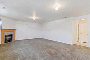 Unfurnished Family room with light colored carpet and a tiled fireplace