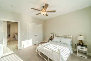 Carpeted bedroom with ceiling fan and a closet