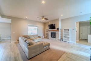 Living room featuring ceiling fan, a fireplace, and light hardwood / wood-style flooring