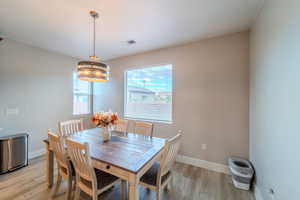 Dining space with light hardwood / wood-style floors and an inviting chandelier