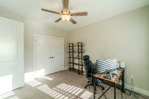 Carpeted office space featuring ceiling fan