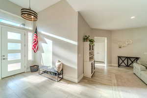 Entrance foyer featuring an inviting chandelier, light hardwood / wood-style floors, and a healthy amount of sunlight