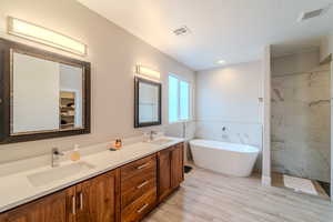 Bathroom with tile walls, vanity, a textured ceiling, independent shower and bath, and wood-type flooring