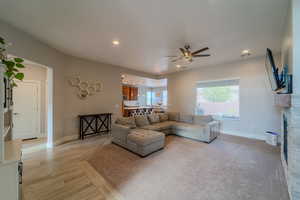 Living room featuring light hardwood / wood-style floors, ceiling fan, and a fireplace