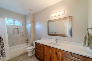 Full bathroom with shower / bath combination with curtain, vanity, toilet, and hardwood / wood-style flooring