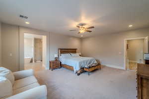 Bedroom with light carpet, ceiling fan, and ensuite bathroom