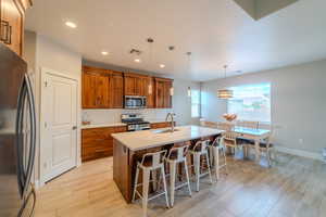 Kitchen with appliances with stainless steel finishes, a breakfast bar, pendant lighting, a center island with sink, and sink