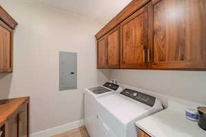 Laundry area featuring cabinets, light hardwood / wood-style flooring, electric panel, and separate washer and dryer