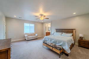 Bedroom with connected bathroom, ceiling fan, and light colored carpet