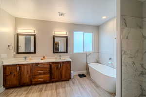 Bathroom with vanity, a bath, and hardwood / wood-style flooring