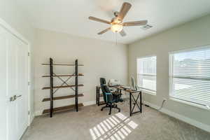 Carpeted office space featuring ceiling fan