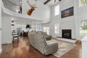 Living room with a towering ceiling, ceiling fan, dark hardwood / wood-style floors, and a healthy amount of sunlight