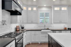 Kitchen with stainless steel appliances, wall chimney exhaust hood, and white cabinetry