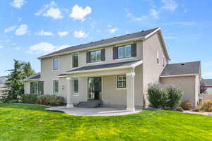 View of back facade with a patio and a back lawn