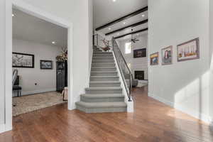 Stairs featuring a towering ceiling, ceiling fan, and hardwood / wood-style floors