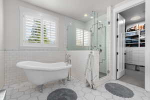 Bathroom featuring tile walls, tile patterned flooring, and plus walk in shower