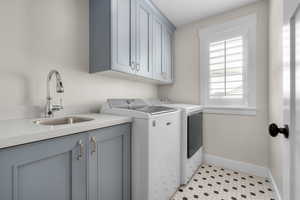 Laundry area featuring cabinets, independent washer and dryer, light tile patterned floors, and sink